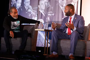 A panelist onstage wearing the 2026 MLK Jr. shirt